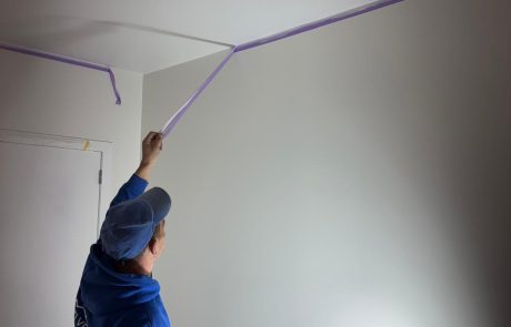 Pose d’un ruban de masquage au plafond avant les travaux de peinture