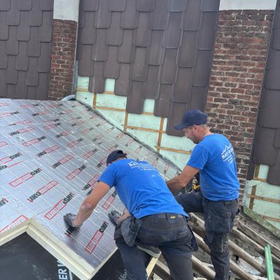 Installation professionnelle d’un isolant thermique sous toiture sur maison en briques avec finition en tuiles