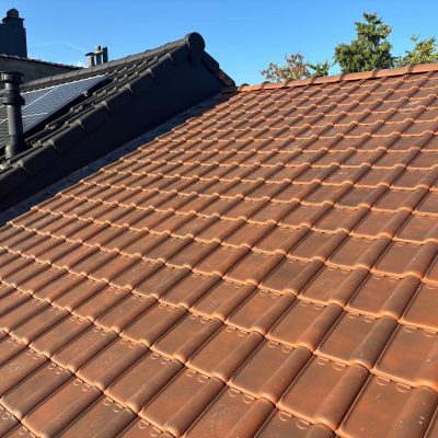 Toiture en pente rénovée offrant une couverture en tuiles homogène et une intégration de panneaux photovoltaïques