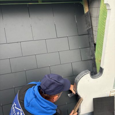 Détail de la rive de toiture rénovée avec couverture en tuiles et chéneau métallique étanche