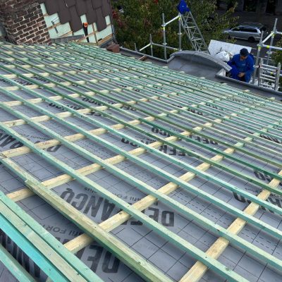 Pose de lattes en bois traitées sur écran de sous-toiture pour une rénovation complète de toiture en tuiles.